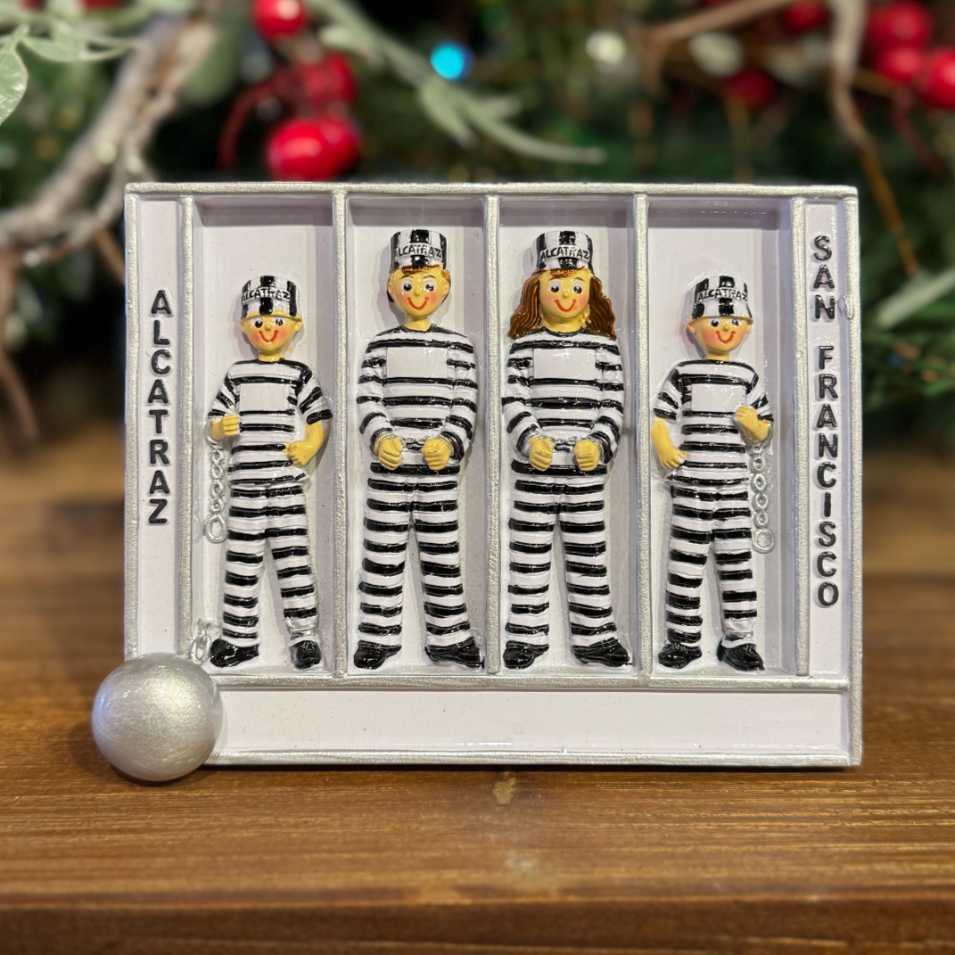 Set of four prison-themed figures in a jail cell tabletop with 'Alcatraz' and 'San Francisco' text, on a wooden surface.